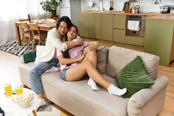 Bir çift kanepede sıcak bir kucaklaşmanın tadını çıkarır, rahat ve davetkar bir ev ortamıyla çevrili..