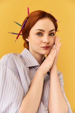 Genç bir kadın saçlarında renkli kalemlerle nazikçe gülümsüyor..