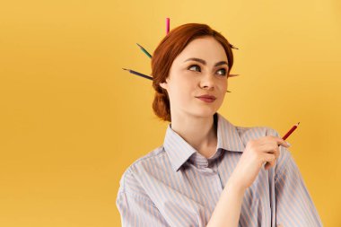 Genç bir kadın sanatsal yeteneğini renkli kalemlerle saçlarında şakaya gelir şekilde ifade ediyor..