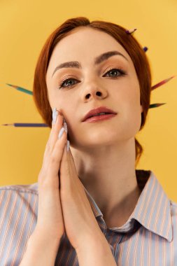 Çarpıcı özellikleri olan genç bir kadın saçına renkli kalemler takmış..