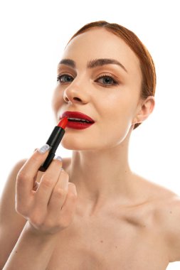 Kendine güvenen genç bir kadın dudaklarına çarpıcı bir kırmızı ruj sürerek güzelliğini geliştirir..