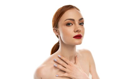 Çekici genç bir kadın özgüvenle poz verir. Basit bir arkaplan karşısında, baştan çıkarıcı bir şekilde..