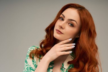 Akan kızıl saçlı güzel genç bir kadın zarif poz verirken stilini ve zarafetini sergiliyor..