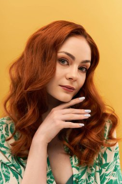Çekici genç bir kadın zarif bir şekilde poz verir. Belirli özelliklerini ve dalgalı kızıl saçlarını sergiler..