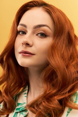 Dalgalı kırmızı bukleleri olan parlak genç kadın güzelliğini ve kendine olan güvenini canlı bir ortamda sergiliyor..