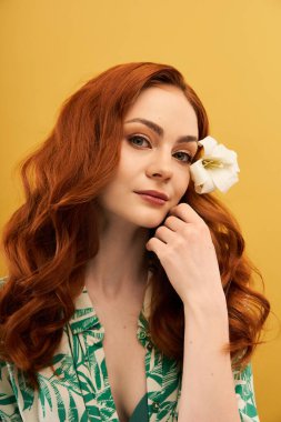 Hoş, genç bir kadın dalgalı kızıl saçlarıyla nazikçe yüzüne dokunuyor bir çiçek saçlarını süslerken..