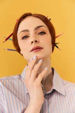 Genç bir kadın saçlarında sanat malzemeleriyle zarifçe poz veriyor, yaratıcılığını ve cazibesini sergiliyor..