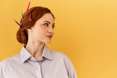 Parlak genç kadın sanatını saçlarında renkli kalemlerle gösteriyor, özgüvenle gülümsüyor..