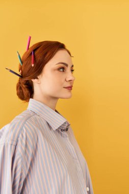 Genç ve güzel bir kadın sanatsal yetenekler sergiliyor saçlarında kalemlerle usulca gülümsüyor..