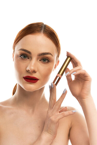 Красивая женщина подчеркивает свои навыки макияжа яркой помадой в хорошо освещенной студии.