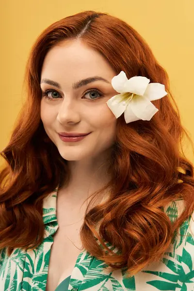 Uçan kızıl saçlı neşeli genç bir kadın çiçek ve tropikal bir gömlek giyer..