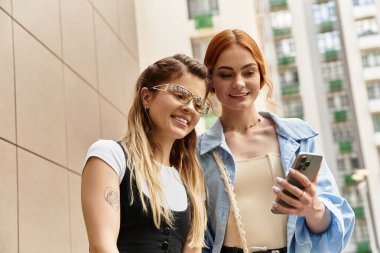 İki şık arkadaş açık havada bir ışık anı paylaşıyor, sohbet ediyor ve birlikte gülümsüyorlar..