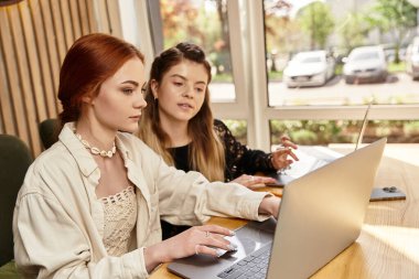 İki genç kadın, modaya uygun bir kafede, fikirleri ve ilhamı paylaşarak, odaklanmış uzaktan çalışmalara girişiyor..