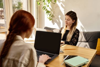 İki genç kadın şık bir kafede dizüstü bilgisayarlarıyla çalışıyor. Birbirine eşlik edip yaratıcılıktan keyif alıyorlar..