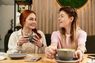 Dostlar kahkahalar ve kahkahalar paylaşır samimi, çağdaş kafe ortamında.