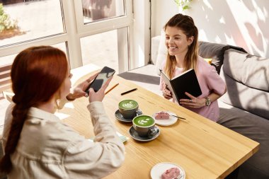 Arkadaşlar modern bir kafede keyifli bir öğleden sonranın tadını çıkarırlar. Matcha latte eşliğinde keyifli anlar yakalarlar..