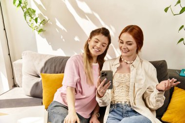 Genç kadınlar modaya uygun bir kafede akıllı telefondan gülüp gülüyorlar..