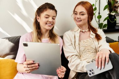 İki arkadaş modaya uygun bir kafede birlikte rahatlıyor, tablet kullanırken kahkahalar ve hikayeler paylaşıyorlar..