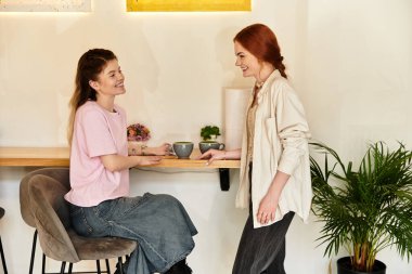 İki genç kadın, modaya uygun bir kafede Matcha yudumlarken gülüp sohbet ediyorlar..