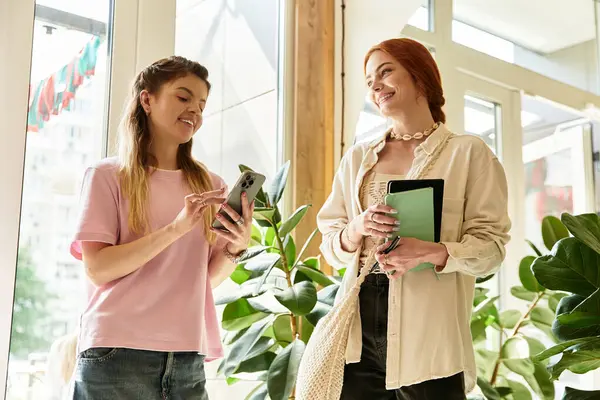 İki güzel genç bayan, şık bir kafede neşeyle sohbet eder, birbirlerine eşlik ederler..