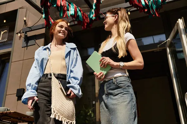 İki güzel genç bayan, şık giyinmiş, dışarıda canlı sohbete girişiyor..