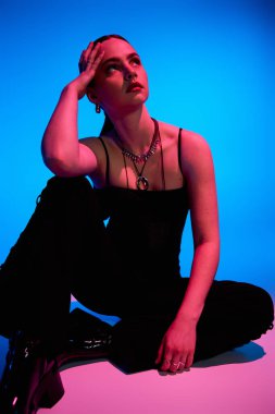 Genç bir kadın canlı bir arka planda şık bir kıyafet modelliği yapıyor..