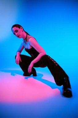 Şık genç bir kadın dinamik bir poz verir, pembe ışıkta yıkanır..