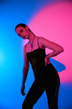 Güzel bir genç kadın, canlı renklerle çevrili bir stüdyoda şık bir kıyafet modelliyor..