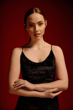 Genç bir kadın siyah bir elbiseyle zarif bir şekilde poz veriyor..