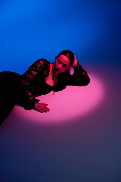 Young woman showcases a fashionable outfit while striking a pose in vibrant studio lighting.
