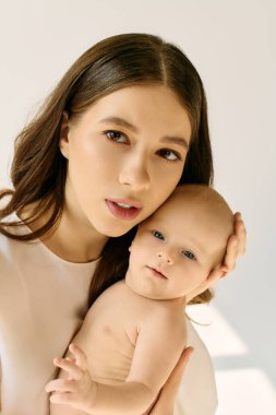 Genç anne sevgiyle çocuğunu kucağına alır, ebeveynliğin sevincini ve sıcaklığını gösterir..