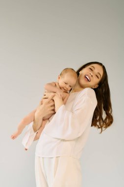 Genç bir anne kıkırdayan bebeğini mutlu bir şekilde parlak bir odada tutarak neşeli anılar yaratıyor..