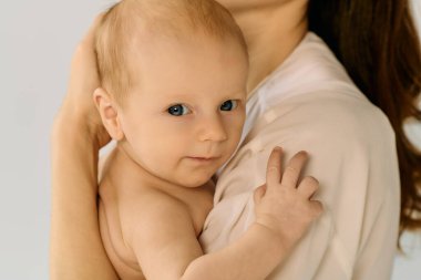 Güzel, genç bir anne, sevgi ve şefkat saçan küçük çocuğunu sevgiyle kucaklıyor..