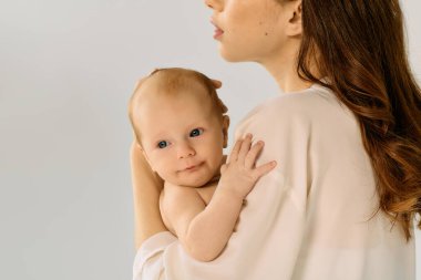 Güzel, genç bir anne, küçük çocuğunu nazikçe kucaklar, sıcaklık ve sevgi saçar..