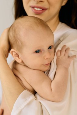 Genç bir anne sevgiyle çocuğunu kucağına alır, sıcacık bir ortamda sıcaklığını yayar..