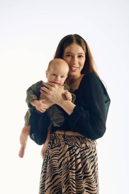 Mutlu, genç bir anne çocuğunu kucaklar. Parlak, sıcak bir ortamda aşk saçar..