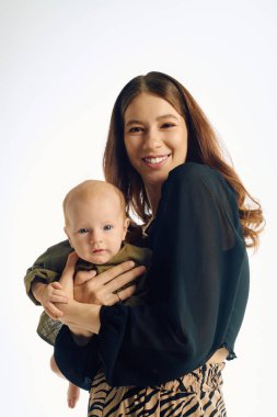 Genç bir anne sevgiyle bebeğini sıcak ve mutluluk saçan parlak bir stüdyoda tutar..