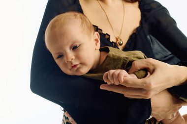 Güzel, genç bir anne, küçük çocuğunu sevgiyle kollarına alır ve bu hassas anı paylaşır..