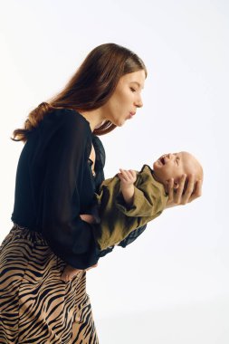 Genç bir anne bebeğiyle sevgi dolu bir şekilde etkileşime girer ve huzurlu bir ortamda neşeli bir bağ yaratır..