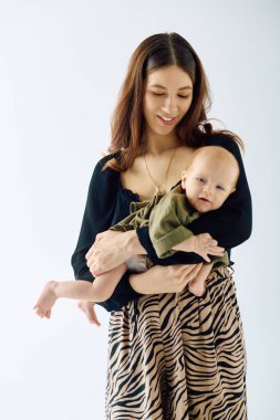 Güzel, genç bir anne sevgiyle kucağına alır ve annelik bağını gösterir..