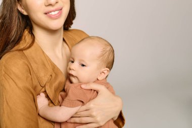 Neşeli bir anne bu hassas anda bebeğini kucağına alır, sıcaklığını ve sevgisini yayar..