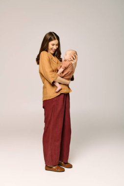 Mutlu bir anne, bebeğini sıcak ve davetkar bir ortamda sevgiyle kucaklar.