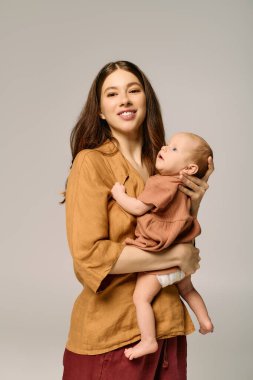 Işıl ışıl bir anne çocuğunu kucağına alıp aile bağlarının güzelliğini kutluyor..