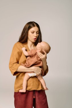 Yumuşak bir ortamda, genç bir anne sevgiyle bebeğini kucaklar ve ebeveynlik bağını gösterir..