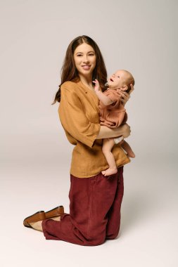 Genç bir anne, mutlu bebeğini sevgiyle kucaklar ve modern bir evde ebeveynliğin neşesini gösterir..