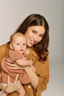 Güzel, genç bir anne sevgi dolu bir şekilde çocuğunu kucağına alır, o anda sıcaklık ve neşe saçar..