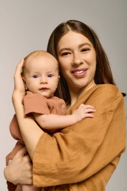 Işıl ışıl sıcaklık ve mutluluk saçan genç bir anne, bebeğini kucağına alır ve hassas bir anı paylaşır..