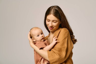 Genç bir anne değerli çocuğunu kucaklar, her ikisi de sevgi dolu bir anda gülümserler..