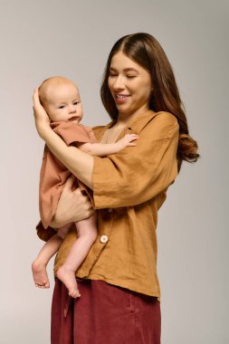 Genç bir anne sıcak ve neşeli bir ebeveynlik anında bebeğini sevgiyle kucaklar..