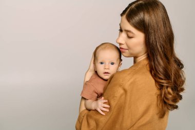 Genç bir anne, bebeğini kucaklarken sevgi ve şefkat saçar..